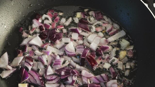 Red onion is fried in boiling oil in a frying pan. Medium plan