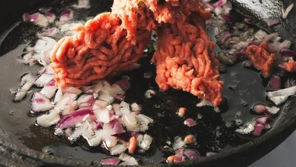 Homemade minced meat falls into a frying pan with onions. Medium plan - Powered by Adobe