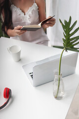 young woman wearing white see through pajamas sits and reads book to review lessons in morning to understand and learn lessons from books because exam time is near. concept of reading books to learn