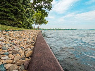 Surface level view of a metal retaining wall dividing the lake from the land. An ornamental stone...