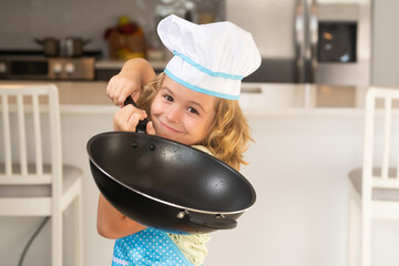 Kid chef cook cookery at kitchen. Cooking, culinary and kids. Little boy in chefs hat and apron.