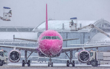 Deicing, airport services de-icing the structure of a pink and white passenger plane, the plane is cleared of people in winter. Flight safety, aviation safety