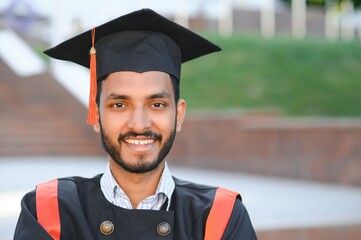 portrait of successful indian student in graduation gown.