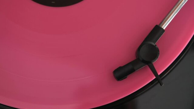 downward view of a rose vinyl record spinning on turntable