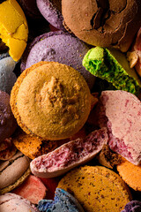 Whole and broken green, violet, brown and orange parts of fresh dessert macaroon laying chaotically