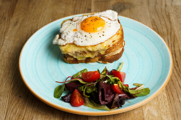 Classic french toast with cheese and ham, fried eggs, vegetables and honey-balsam dressing