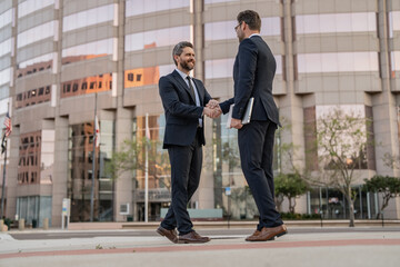 cheerful two business men handshaking. two business men handshaking outdoor.