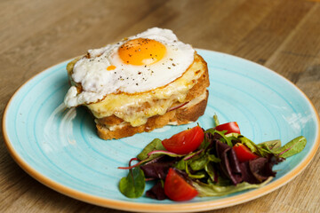 Classic french toast with cheese and ham, fried eggs, vegetables and honey-balsam dressing
