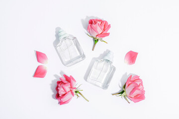 Two perfume bottles and rose flowers on white background with sharp shadows. Beauty, fashion concept. Top view, flat lay, mockup