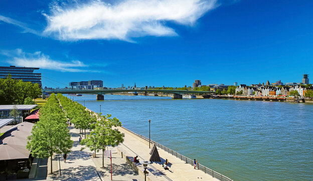 Cologne (K&ouml;ln Deutz, Kennedy-Ufer), Germany - June 6. 2023: Beautiful rhine bank riverside boardwalk, Deutzer bridge, sunny summer day