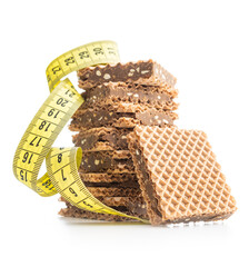 Sweet chocolate wafer and measuring tape isolated on white background.