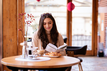 Attractive young woman sitting in a cafe and reading a book
