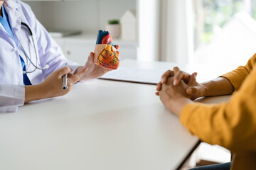 Cardiologist doctor showing anatomical of human heart to patient, heart disease.