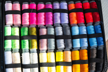 Sewing layout with multicolored spools of thread close-up, needles, coils of thread in a special organizer, organization of storage.