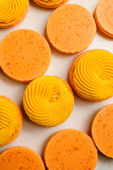 Set of fresh orange halves of meringue based dessert macaron decorated with mango ganache, close up.