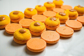 Set of of meringue based shells of dessert macaron decorated with ganache, and salted caramel
