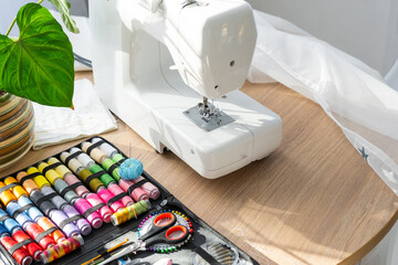 Sewing layout with multicolored spools of thread close-up, needles, electric sewing machine. Filling the thread into the sewing needle, adjusting the tension. hobby, home business