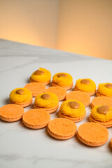 Meringue based shells of dessert macaron decorated with ganache, and salted caramel on marble table.