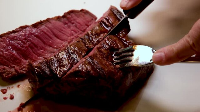 I cut a piece of beef steak in half with a knife on a wooden cutting board, close-up shot, medium doneness. High quality 4k footage