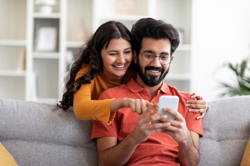 Mobile Gaming. Cheerful Indian Couple Playing Online Games On Smartphone At Home