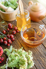 herbal medicine composition linden herb tea, honey, rose hips and goji berries on a old wooden table 