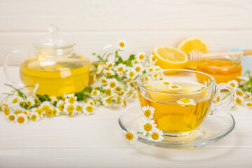 Chamomile tea in a glass cup on a white texture background. Natural hour with chamomile flowers. Herbal tea. Immunity tea.Natural healer concept. Healthy detox drink.Close up. Place for text.