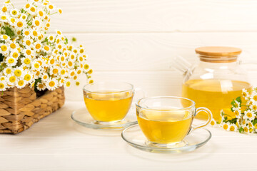 Chamomile tea in a glass cup on a white texture background. Natural hour with chamomile flowers. Herbal tea. Immunity tea.Natural healer concept. Healthy detox drink.Close up. Place for text.