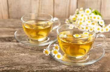 Chamomile tea in a glass cup on a brown textured background. Natural hour with chamomile flowers. Herbal tea. Immunity tea.Natural healer concept. Healthy detox drink.Close up. Place for text.