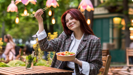 A woman eating a poke in a park