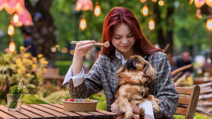 A woman with dog eating a poke in a park