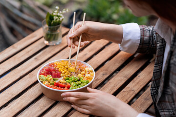 A woman eating a poke in a park
