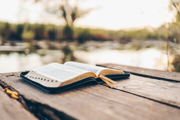 Open Bible on a wooden board near the river
