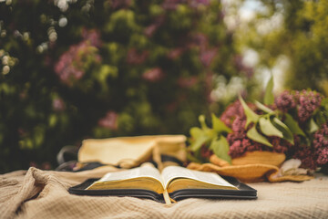 Open bible in the garden and lilac, christian concept