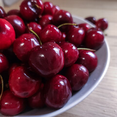 Ripe cherries with water drop on a white plate. Summer berries on a light background.