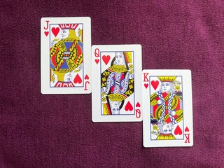 Jack, queen, and king of hearts on red-purple background