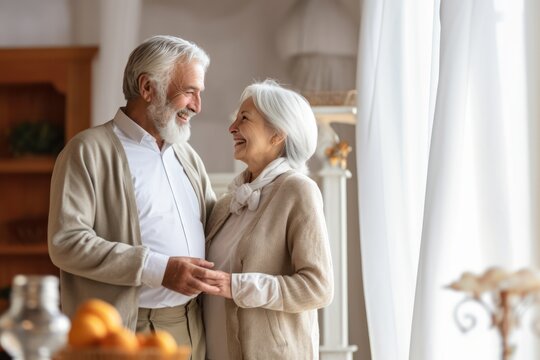 Exuding joy and love, a grey-haired senior couple holds hands, smiles brightly at home.
