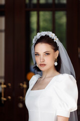 Fototapeta premium portrait of a beautiful bride in a white dress with a veil and a hoop of flowers.