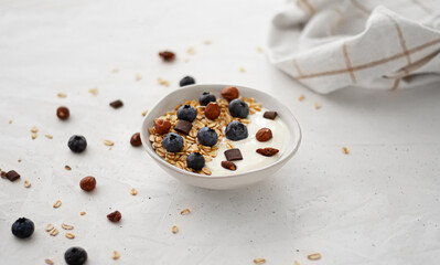 yogurt with granola and blueberries with scattered berries on the table. healthy breakfast rich in minerals and fiber