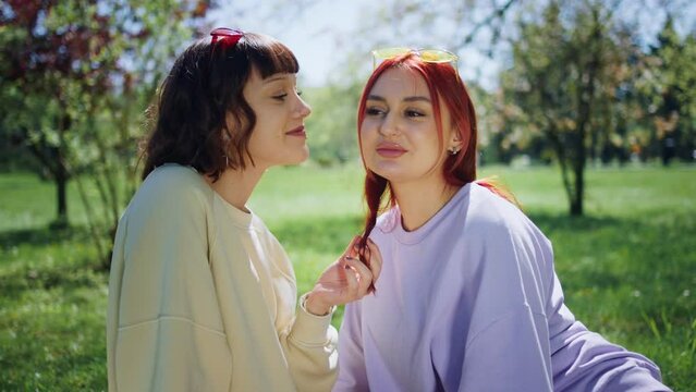 Closeup to the camera in the middle of the park amazing lesbian ladies chilling on the grass one of the lady giving a kiss to other one