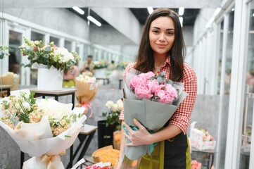 Beautiful florist at flower shop. Woman working in floral shop with copy space. Successful florist smiling