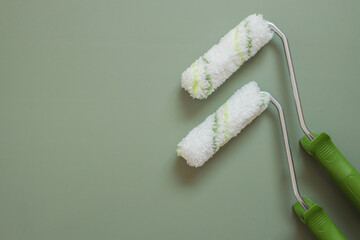 Obraz premium Two rollers for painting walls on a green background, top view