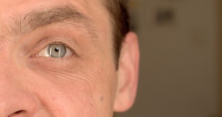 Close-up of the man's left eye raises lowers an eyebrow. Element of manifestation of emotion on the face. Glare in the pupil.