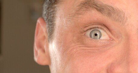 Close-up of the man's right eye. Joyful emotion on the face. He blinks, raises an eyebrow, the movement of facial muscles, wrinkles under the eye.