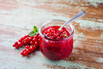 Reife rote Johannisbeeren aus biologischem Anbau und Marmelade in Nahaufnahme auf einem braunen Board mit Textfreiraum