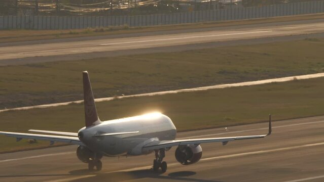 Plane taking off at Phuket airport, sunset backlight. Seawater shine. Passenger flight departure. Travel concept