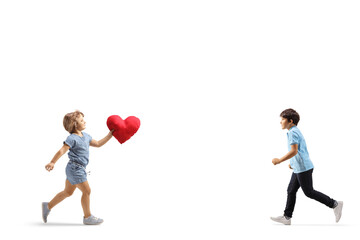 Little girl carrying a red heart and running towards a boy