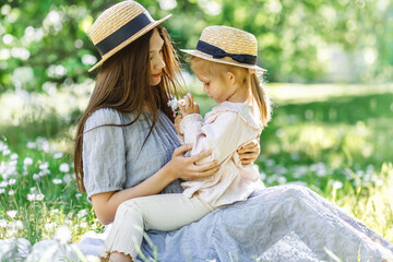 Daughter present flowers Bouquet for her Mother. Little Girl in straw hat hold Young mom in blue dress Nose Giving Chamomiles Present. Family Love and Leisure Landscape nature Field on Background