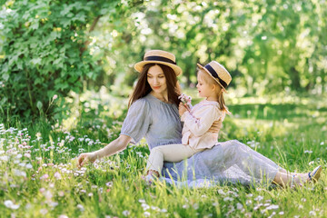 Daughter present flowers Bouquet for her Mother. Little Girl in straw hat hold Young mom in blue dress Nose Giving Chamomiles Present. Family Love and Leisure Landscape nature Field on Background