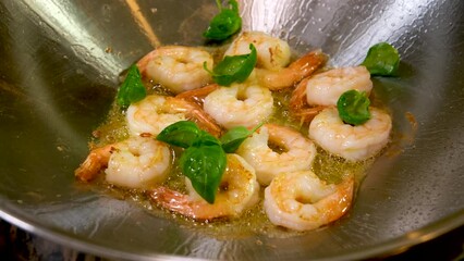 slow motion video very beautiful food sprinkle shrimp simmering in oil with basil in frying pan Wok sprinkles oil closeup oriental seafood cooking restaurant serving