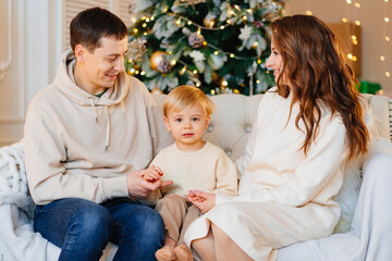 happy family. mom, dad and son on the couch by the Christmas tree.